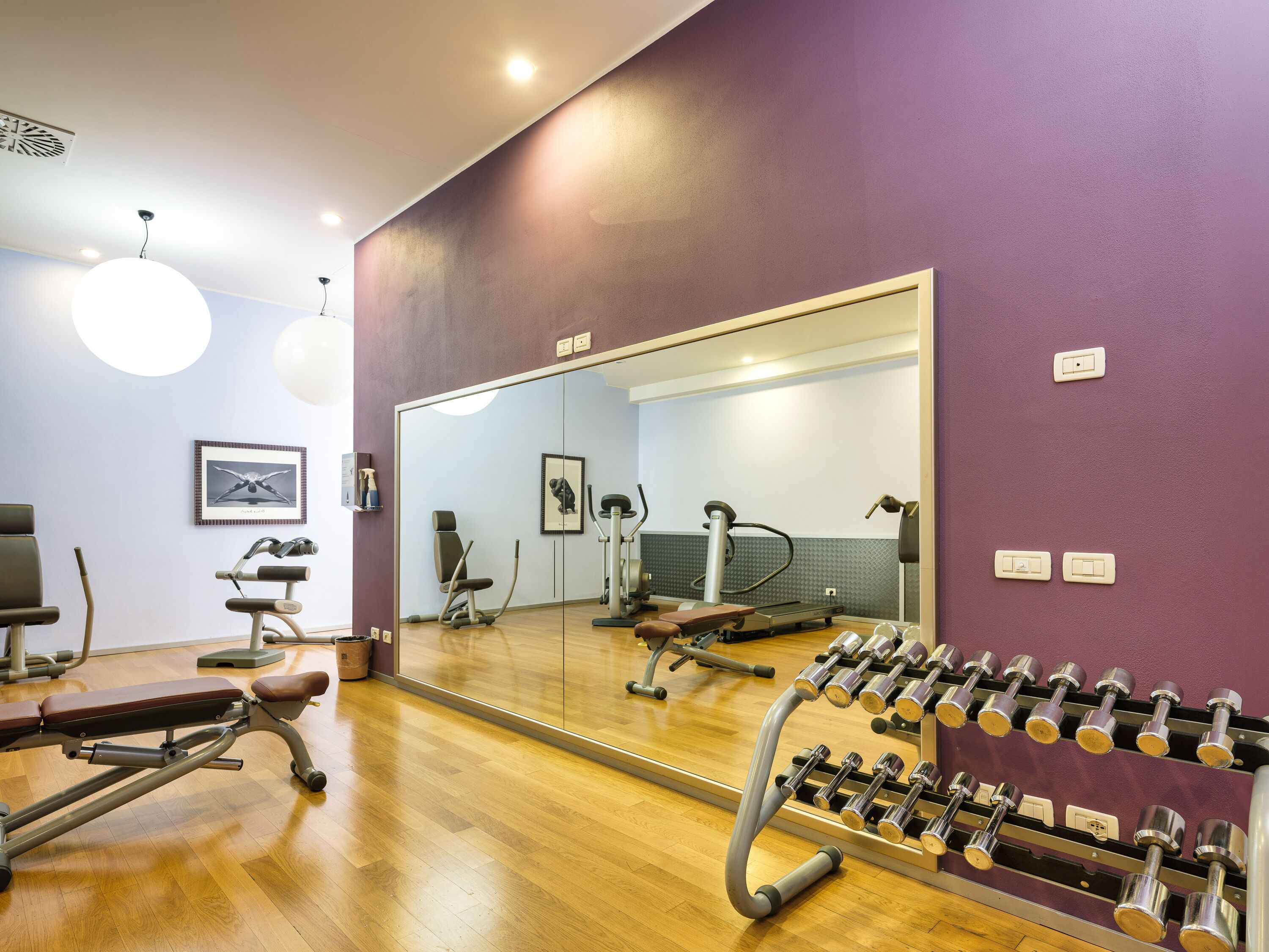 A gym with exercise equipment, a bench, and a mirror.