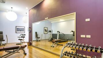 A gym with exercise equipment, a bench, and a mirror.