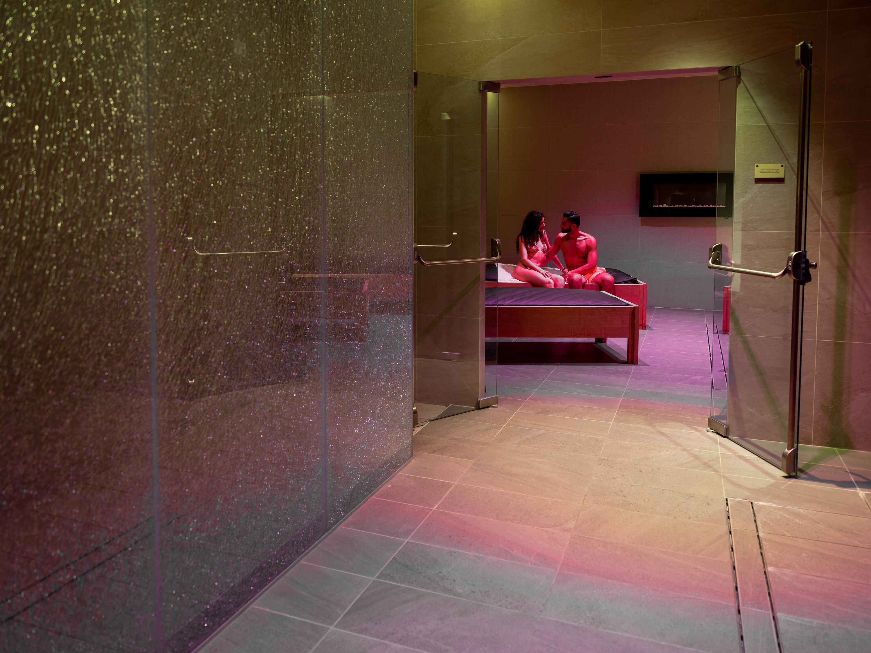 A room with a bed, a glass partition, and a tiled floor.