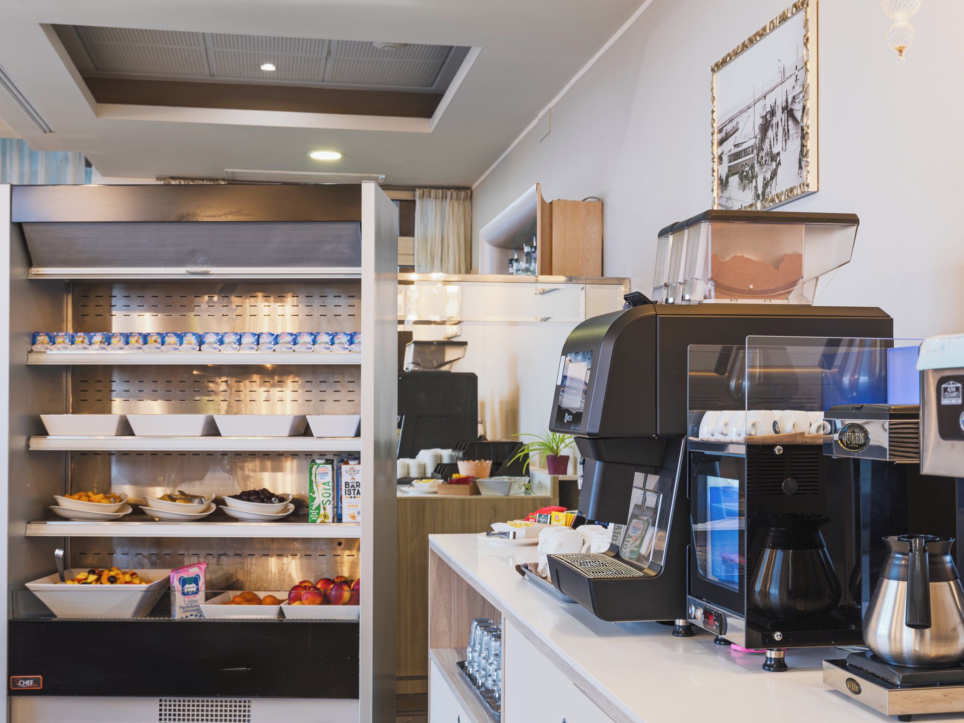 A coffee shop interior with a counter, espresso machines, and shelves stocked with snacks and beverages.