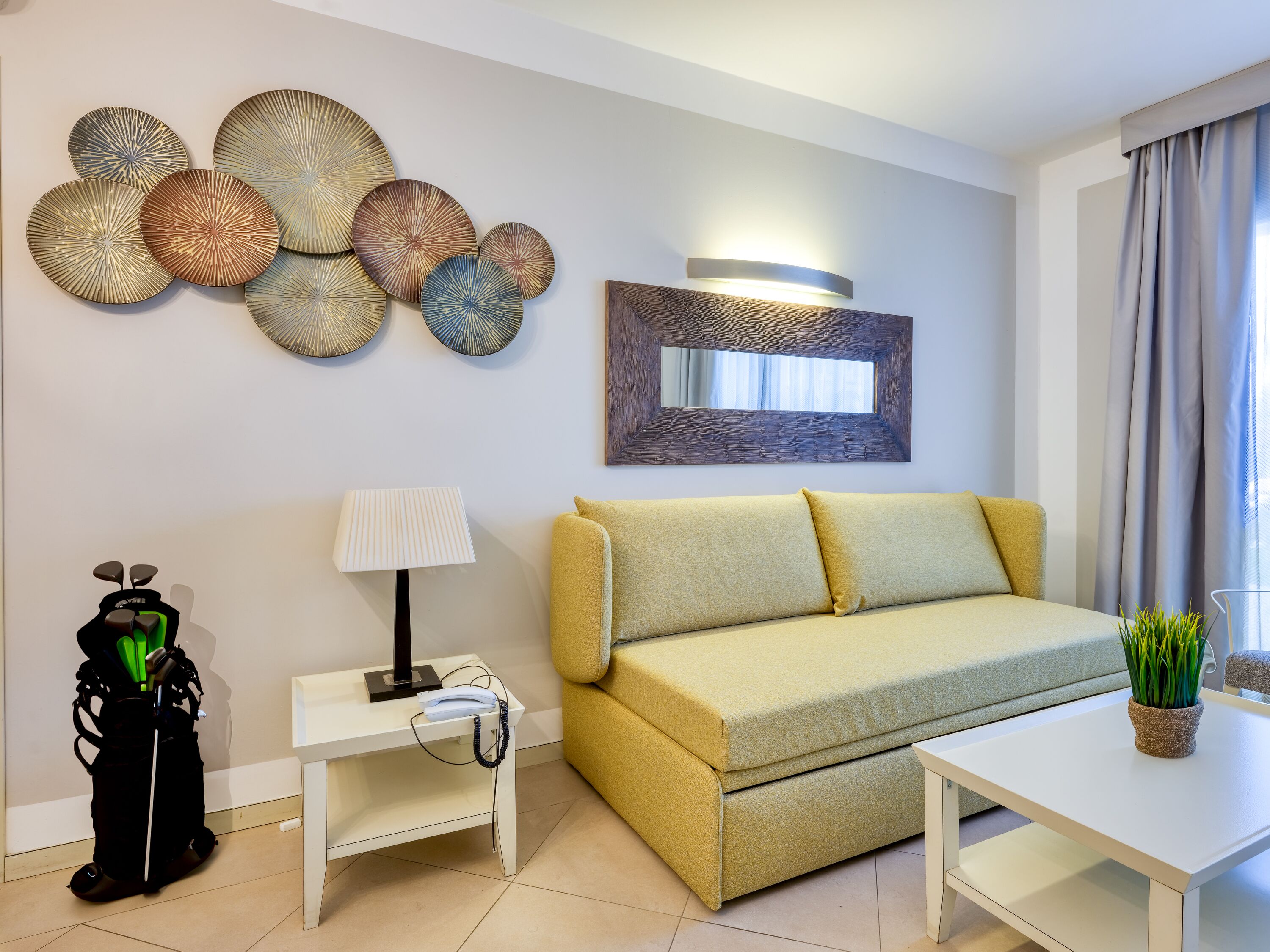 Una sala de estar moderna con un sofá, una mesita de centro, una lámpara y detalles decorativos en la pared.