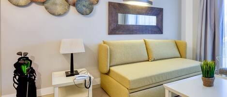 Una sala de estar moderna con un sofá, una mesita de centro, una lámpara y detalles decorativos en la pared.