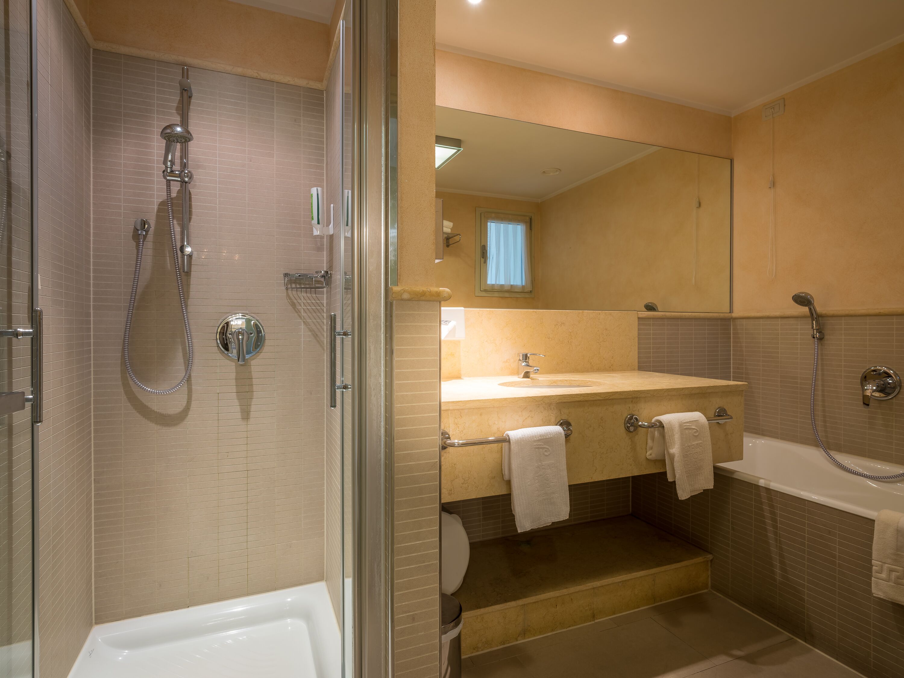 A modern bathroom with a glass-enclosed shower, a bathtub, and a sink with a mirror above it.