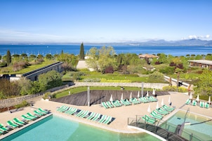 Zona de piscina con numerosas tumbonas y vista al mar.