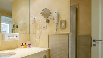 Une salle de bain équipée d’un lavabo, d’un miroir, d’un sèche-cheveux et d’un porte-serviettes.