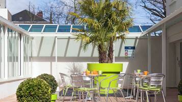 Relax on the patio with a round table and six chairs, surrounded by lush greenery and a view of the surrounding area.