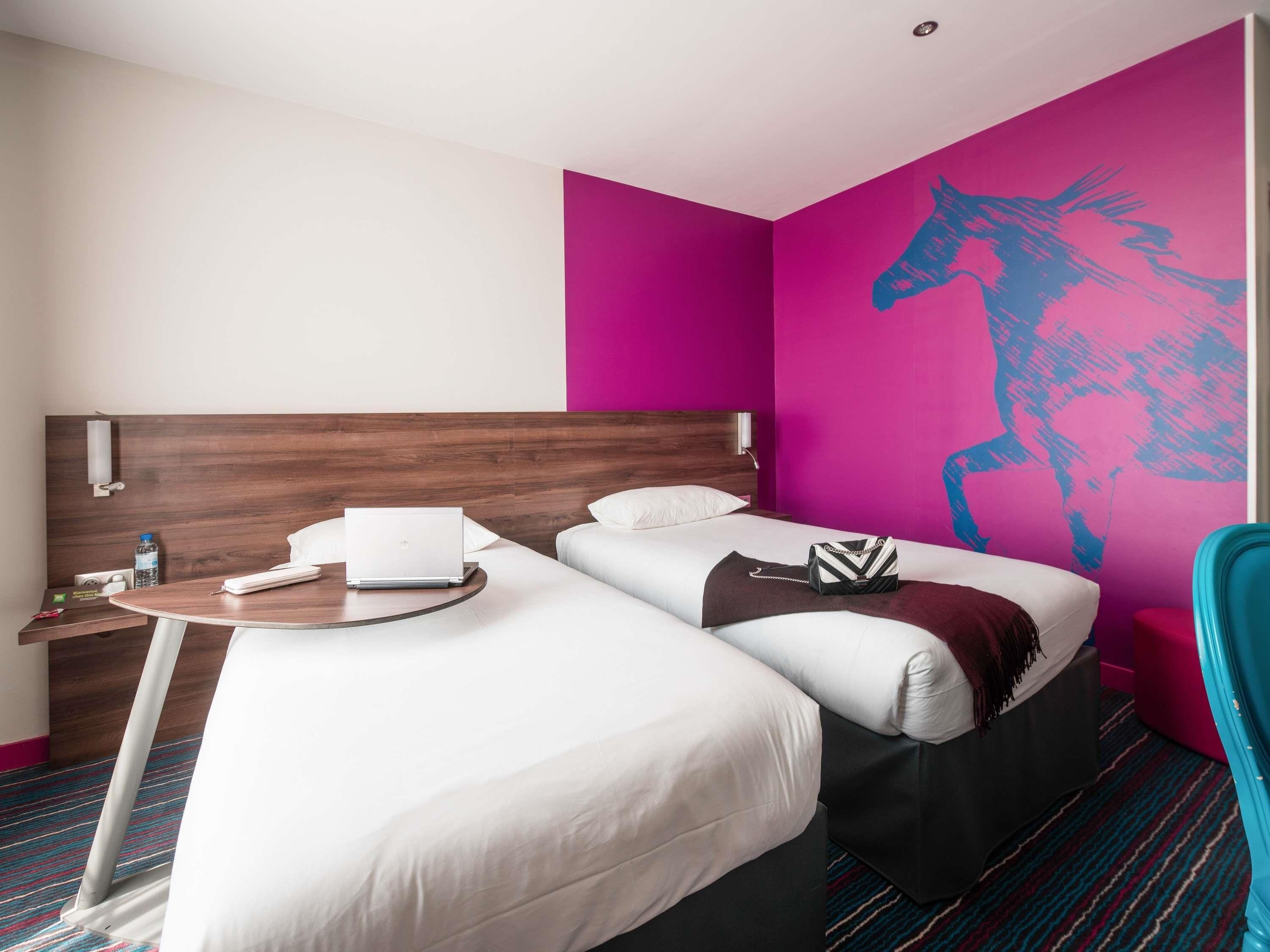 A hotel room with a bed, a desk, and a chair.