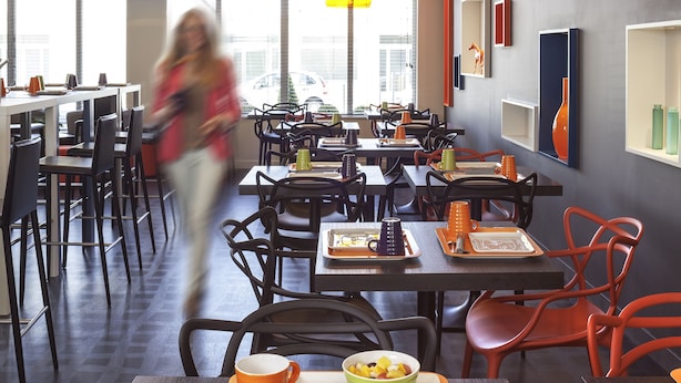 Un espace de restauration moderne, doté de plusieurs tables et chaises, offrant une variété de possibilités d’assise, et bénéficiant d’un intérieur lumineux grâce à la lumière naturelle.