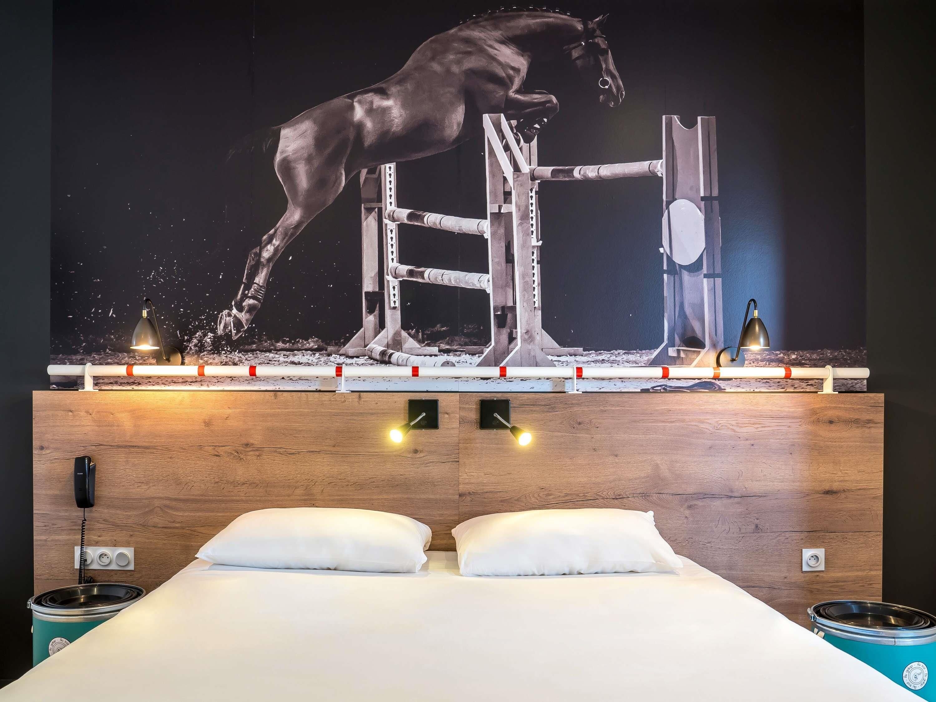 A bed with white bedding, a wooden headboard, bedside lamps, and a wall-mounted phone.