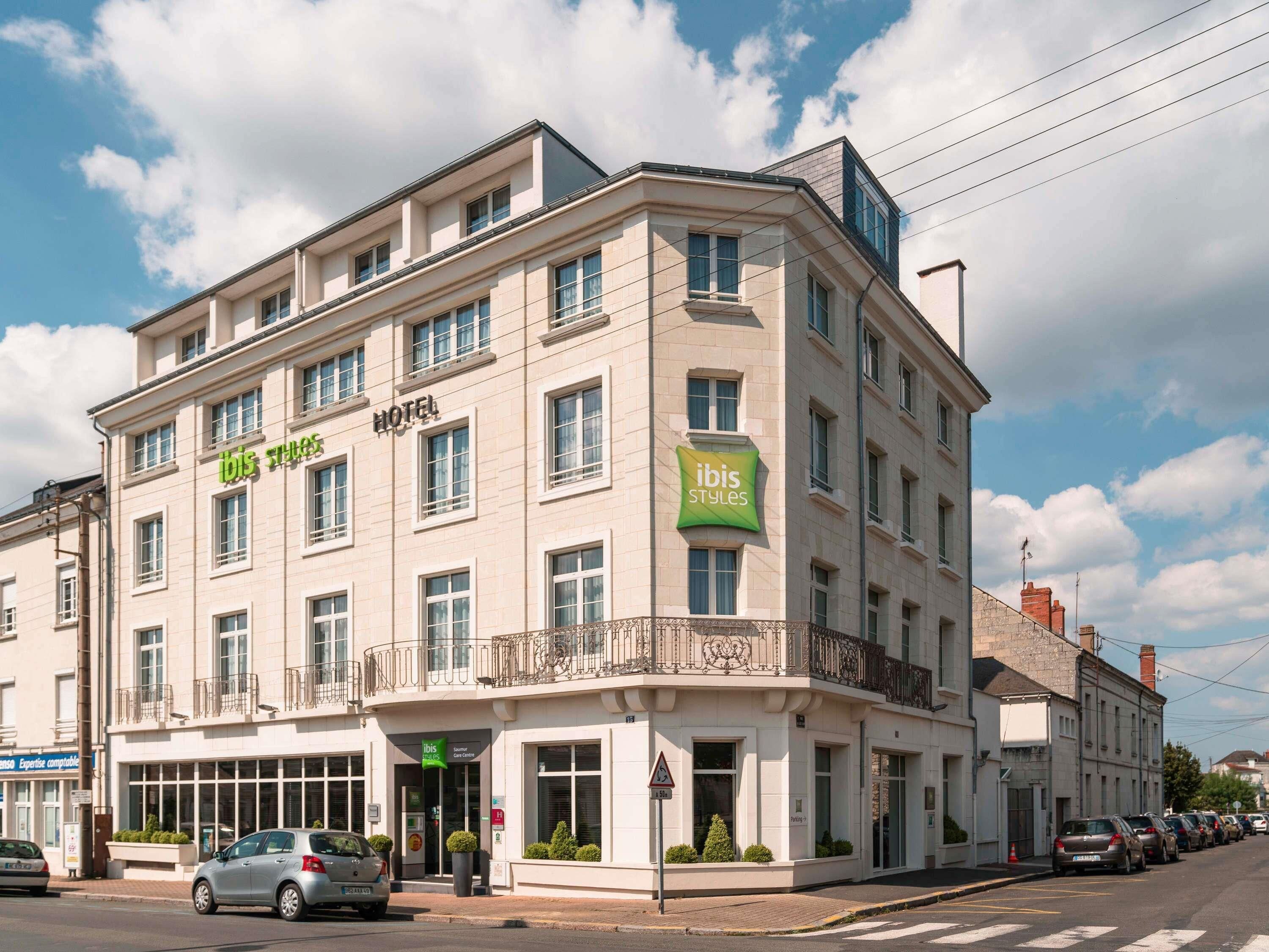 Un hôtel à plusieurs étages, arborant l’enseigne « ibis Styles », avec une entrée au niveau du sol et un espace de stationnement.