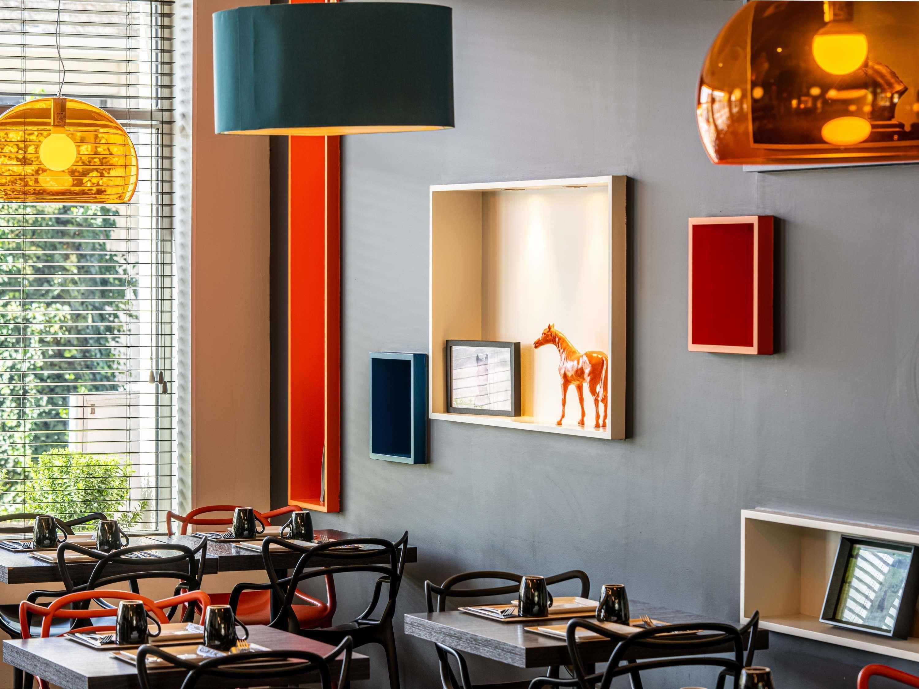 A restaurant interior with tables, chairs, pendant lighting, and wall-mounted decor.