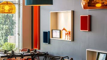 A restaurant interior with tables, chairs, pendant lighting, and wall-mounted decor.