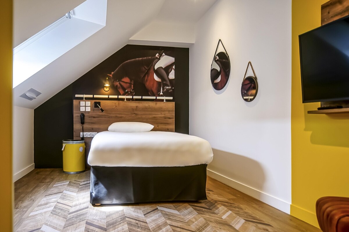 A bedroom with a bed, a wooden headboard, a wall-mounted TV, and a ceiling light.