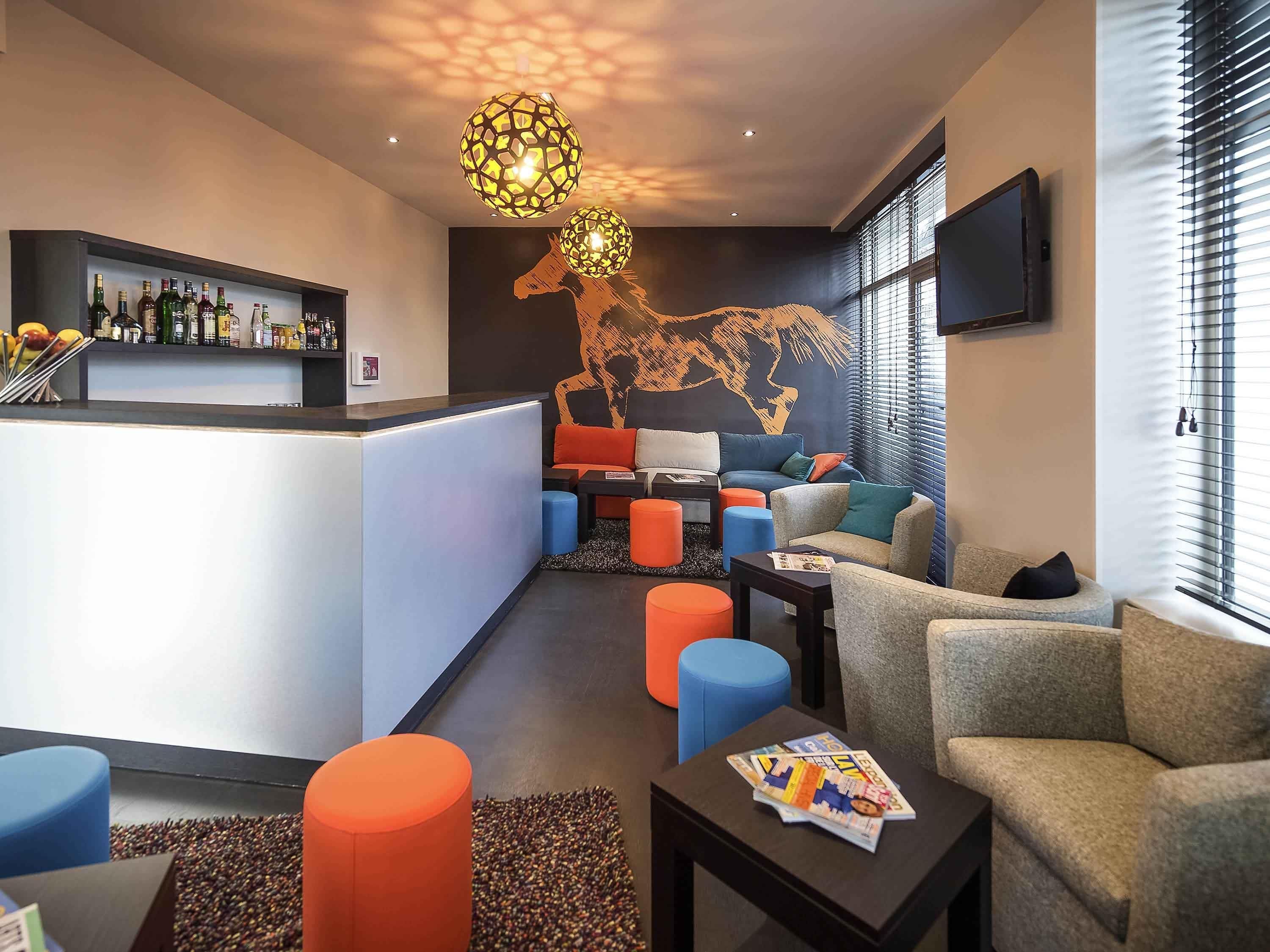 Un espace lounge moderne doté d’un bar, de sièges et d’une fresque représentant une carte du monde.