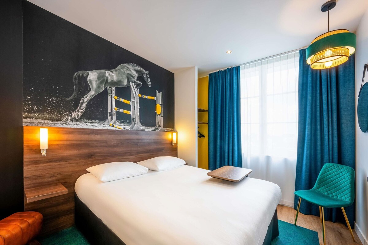 Una habitación de hotel moderna con una cama grande, una obra de arte de un caballo colgada en la pared, un escritorio y una silla.