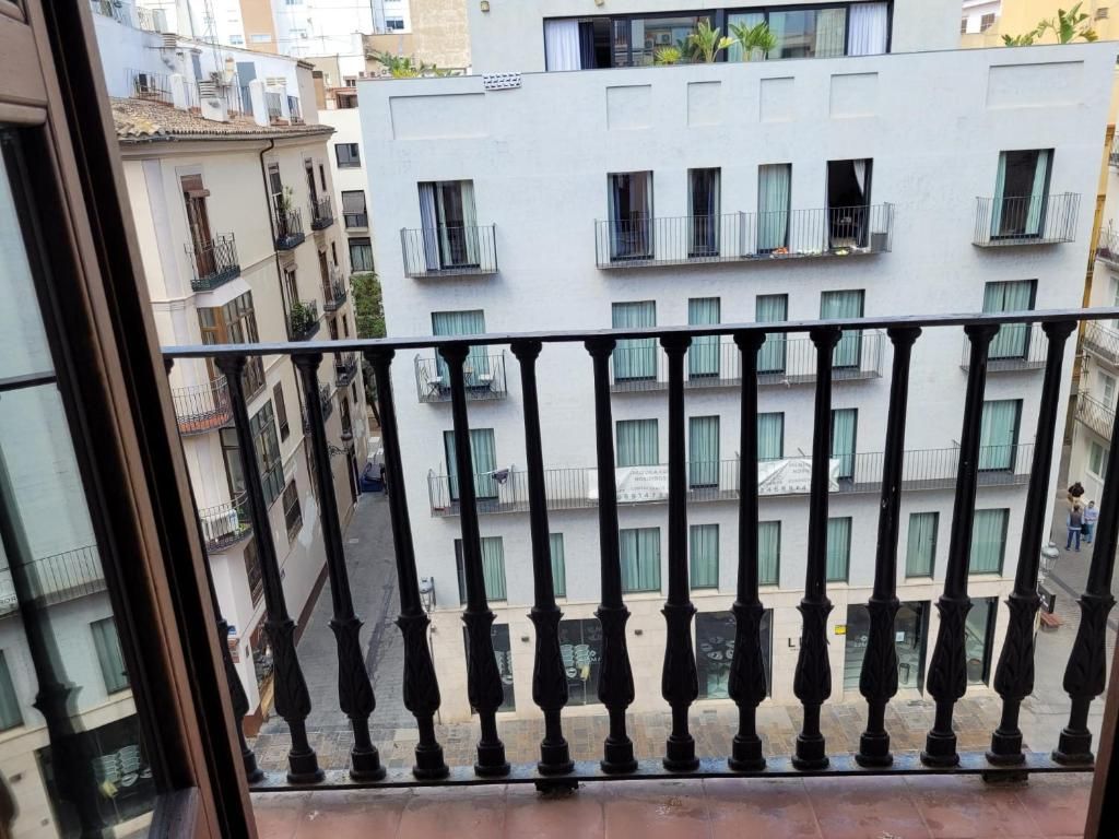 A balcony with a black balustrade overlooking a street with buildings.