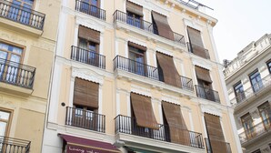 En bygning med flere etager, altaner, store vinduer med markiser, og et skilt med teksten "Living Valencia".