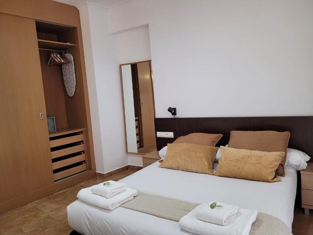 A hotel room with a bed, a wardrobe, and a mirror.