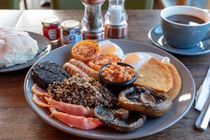 Un plato de comida para el desayuno con huevos, tocino, champiñones, frijoles y tostadas.