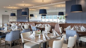 Un restaurante moderno con mesas altas, sillas tapizadas e iluminación colgante.