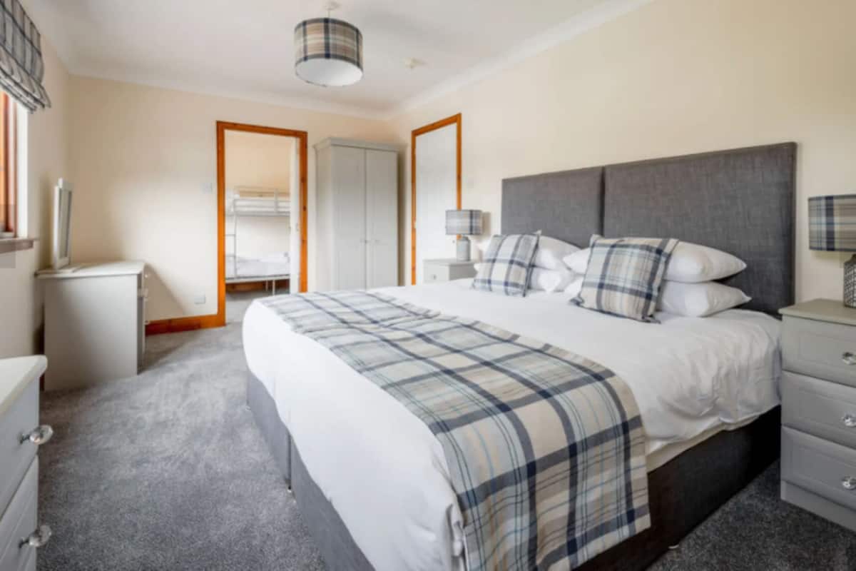 A bedroom with a large bed, bedside tables, a wardrobe, a mirror, and a ceiling light.