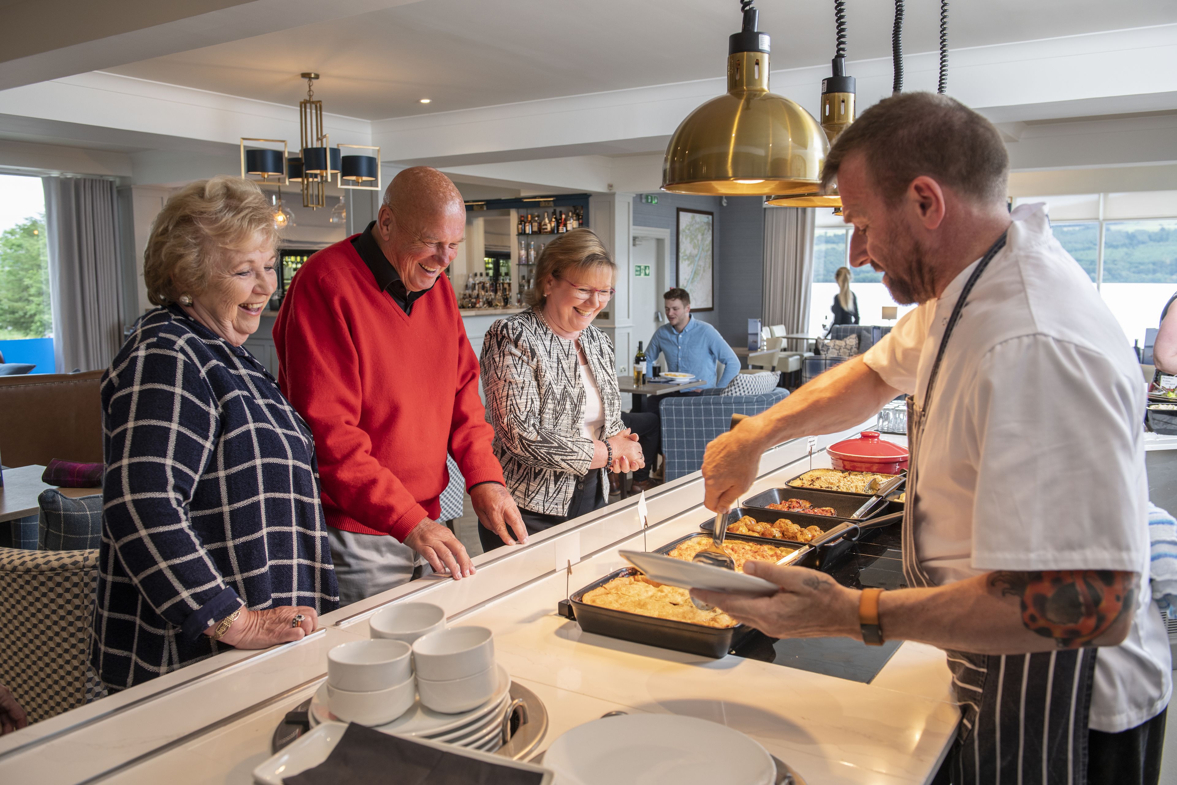 En buffetopsætning med en disk, tallerkener og serveringspersonale.