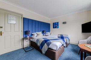 Una habitación de hotel con una cama, mesitas de noche, una silla y un televisor.