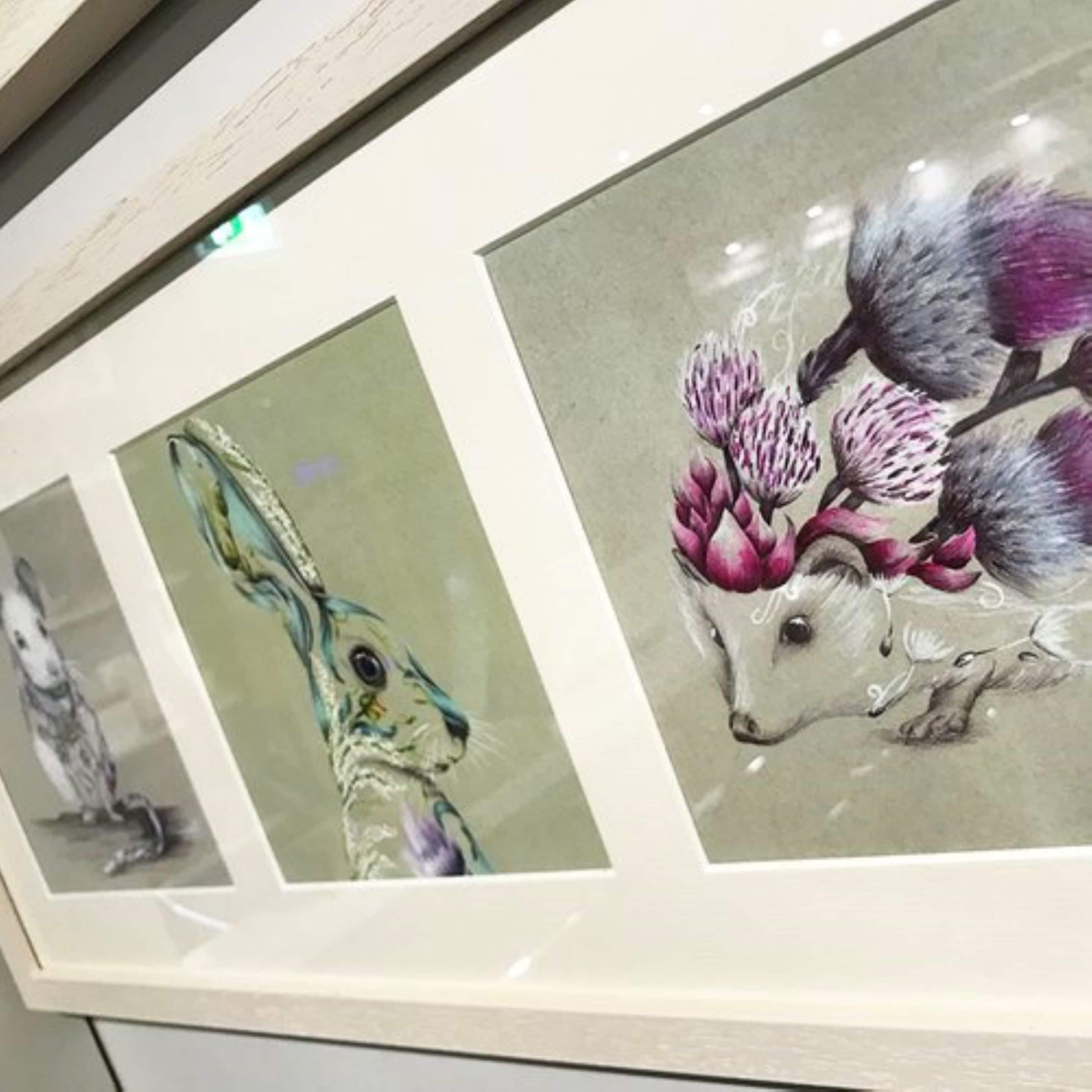 A framed artwork featuring a rabbit and a dog with flowers on their heads.