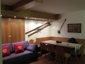 A cozy living area with a sofa, a dining table, and chairs. There is a wooden ceiling with exposed beams and recessed lighting. - Il Piccolo Residence (Gressoney-la-Trinite)