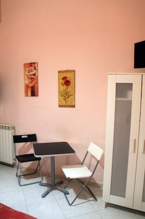 Una habitación con una mesa, dos sillas, un radiador y un armario.