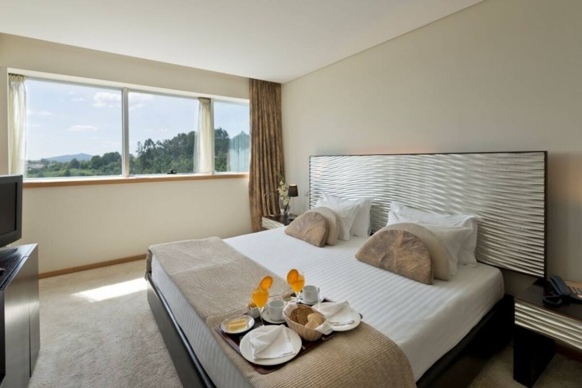 Une chambre d’hôtel avec un grand lit, une télévision et un plateau de petit-déjeuner posé sur le lit.