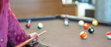 A pool table with balls and a cue stick.