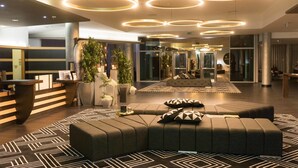 A modern lobby with a reception desk, seating area, and circular ceiling lights. - Penafiel Park Hotel & Spa (Penafiel)