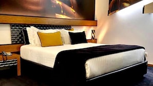 A modern hotel room with a large bed, a headboard with a built-in TV, and a large wall painting. - Penafiel Park Hotel & Spa (Penafiel)