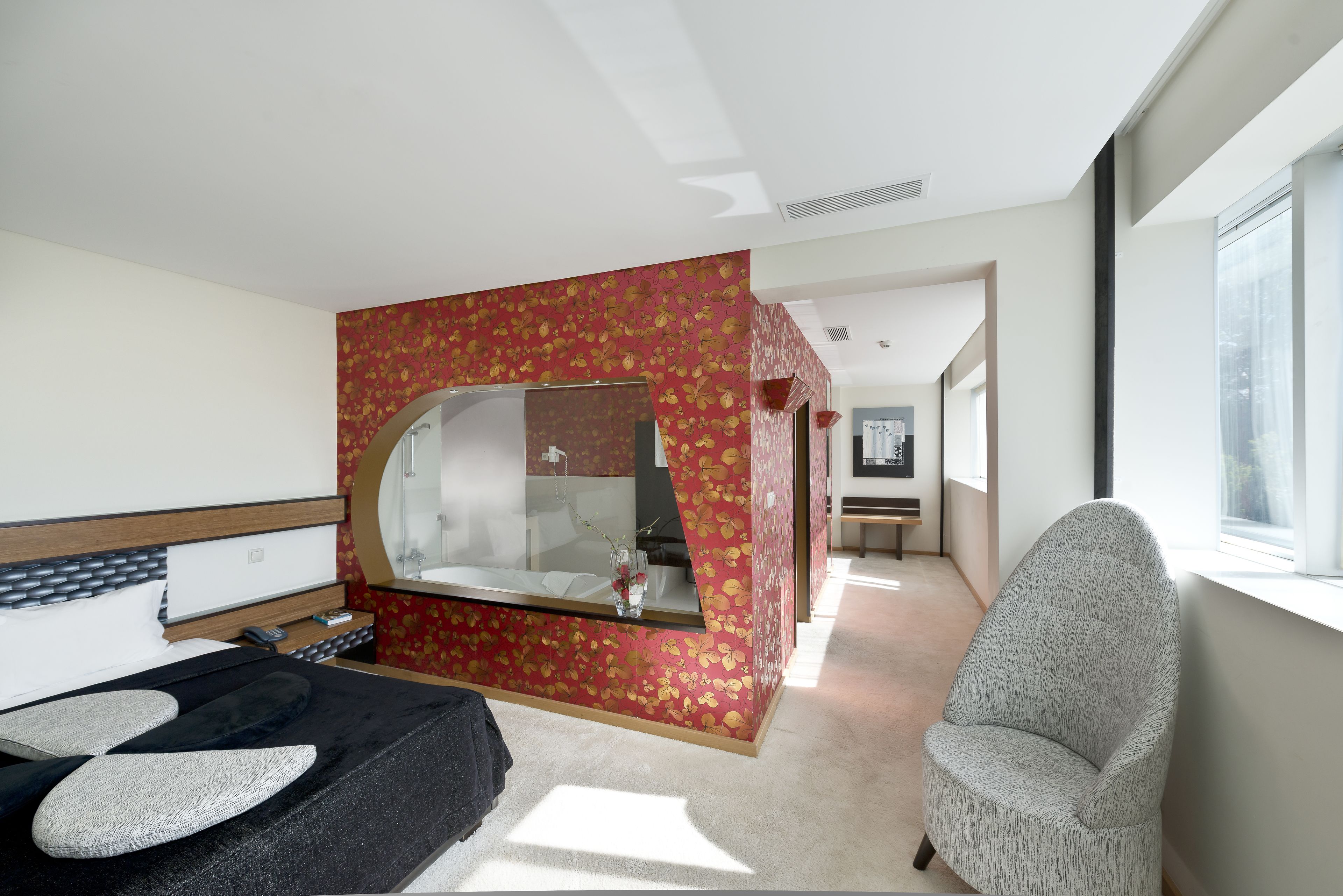 Un dormitorio moderno con una cama, una silla, un tocador y un espejo grande.