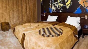 Una habitación de hotel con dos camas, un cuadro abstracto grande en la pared y una mesita de noche de madera.