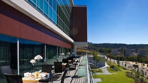 A modern outdoor dining area with tables and chairs, overlooking a landscaped garden and a view of the surrounding area. - Penafiel Park Hotel & Spa (Penafiel)