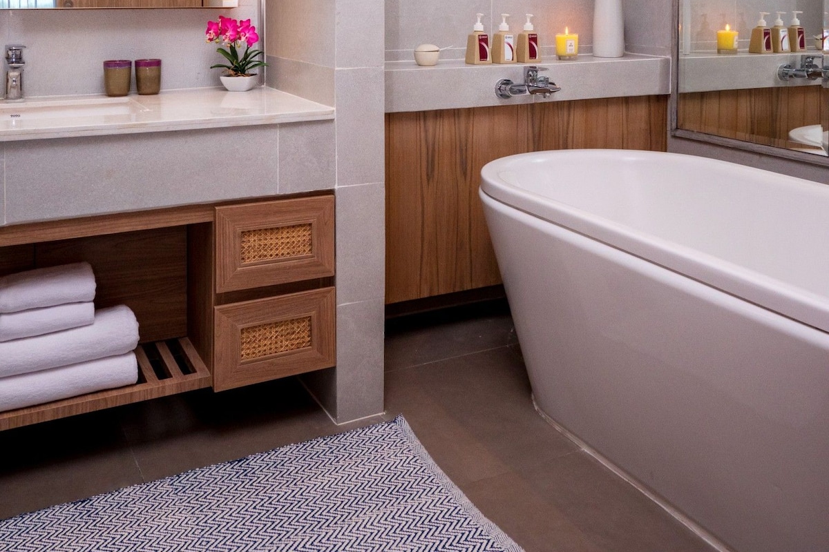 A modern bathroom with a freestanding bathtub, a vanity with a mirror, and a shower area.