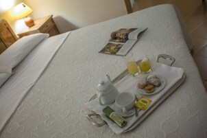 A neatly made bed with a tray of breakfast items including tea, juice, and pastries.