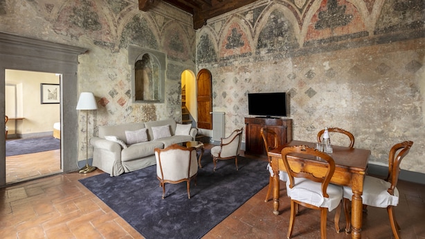 A living room with a sofa, chairs, a table, and a TV. The room has a tiled floor and a fireplace. - Numa Florence Palazzo Belfiore (Florence)