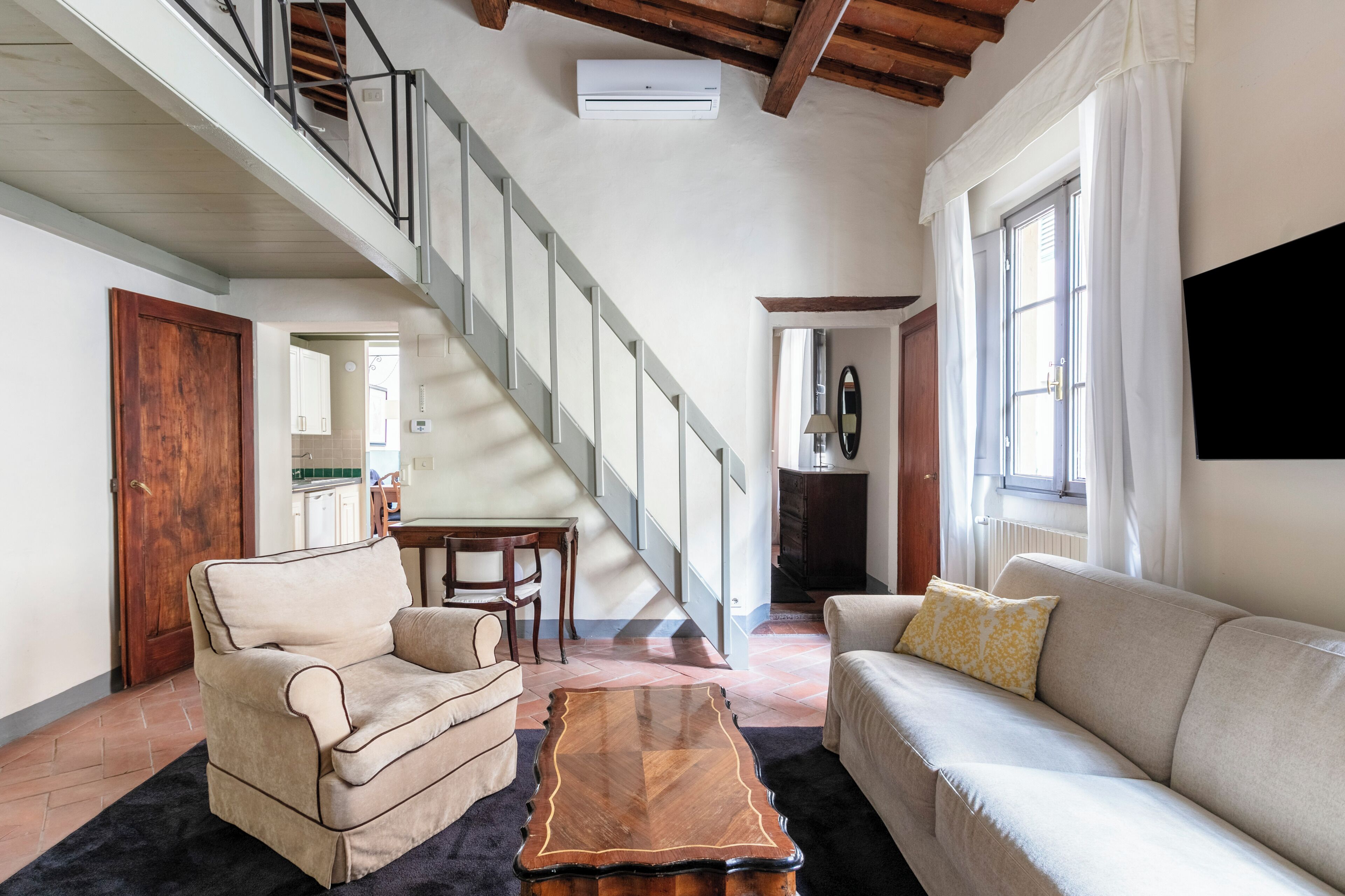 A spacious living room with a staircase, a wooden coffee table, and a sofa.