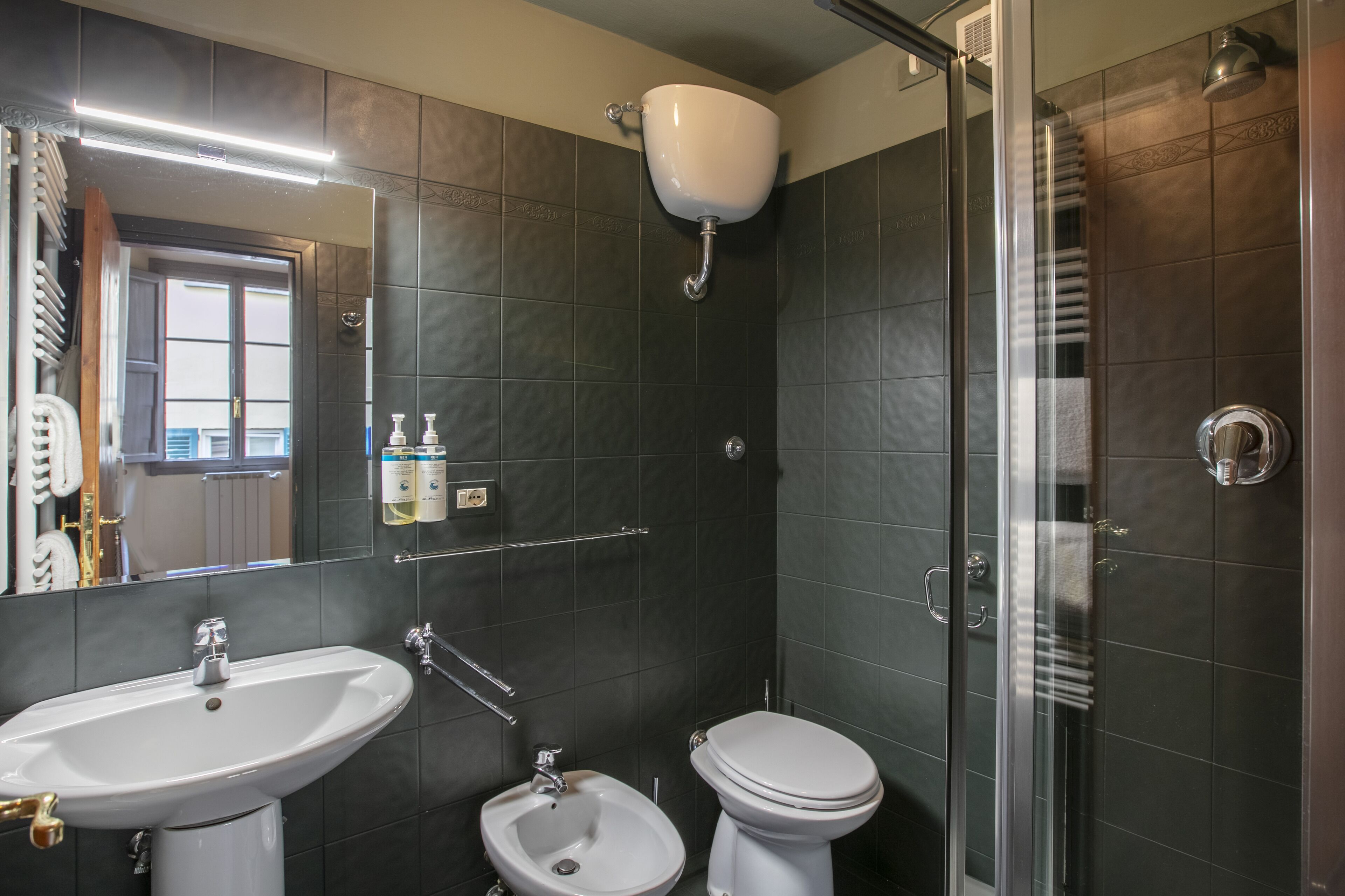 A modern bathroom with a sink, bidet, toilet, and glass shower enclosure.