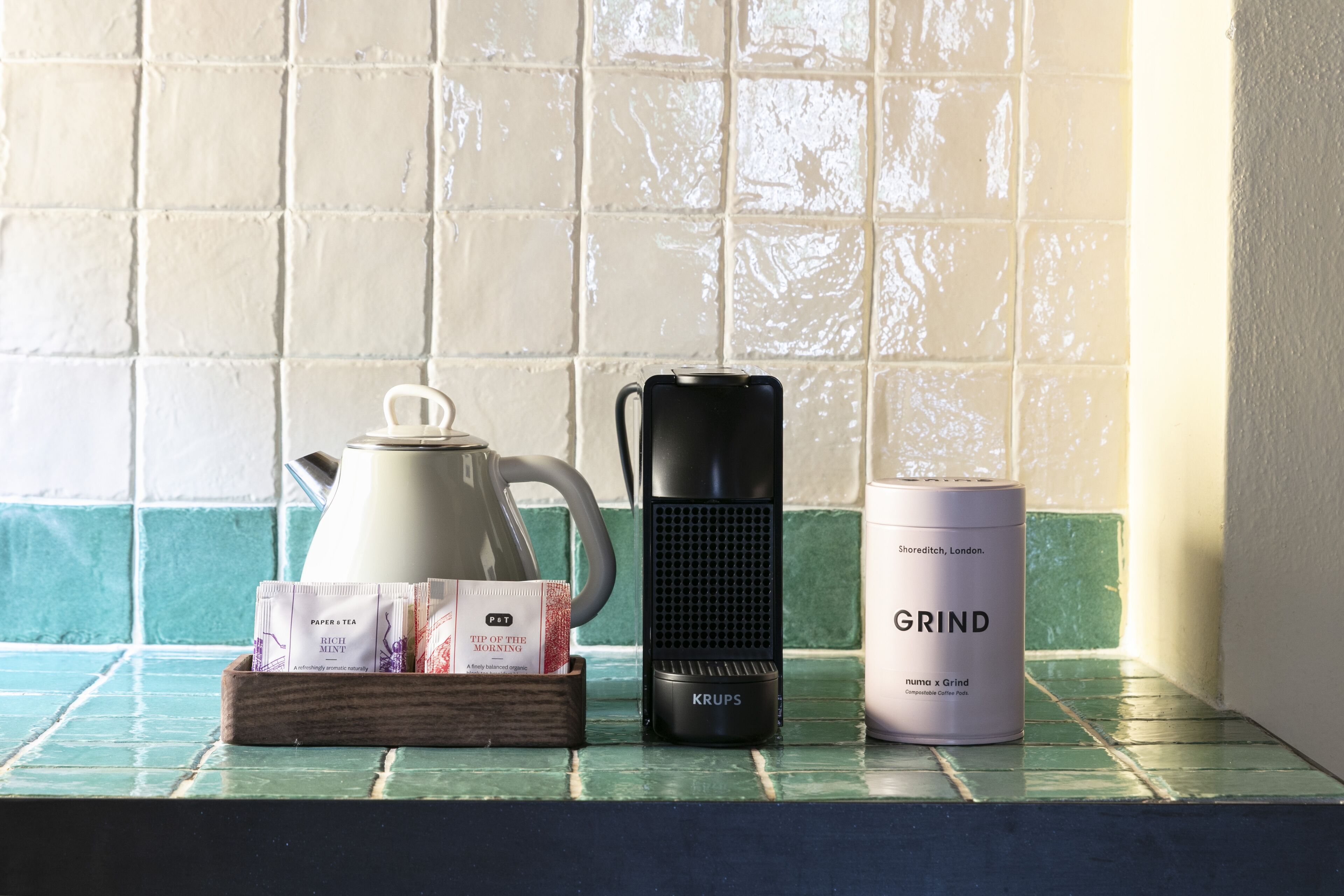 A kitchen counter with a coffee maker, a grinder, and tea packets.