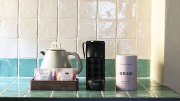 A kitchen counter with a coffee maker, a grinder, and tea packets.