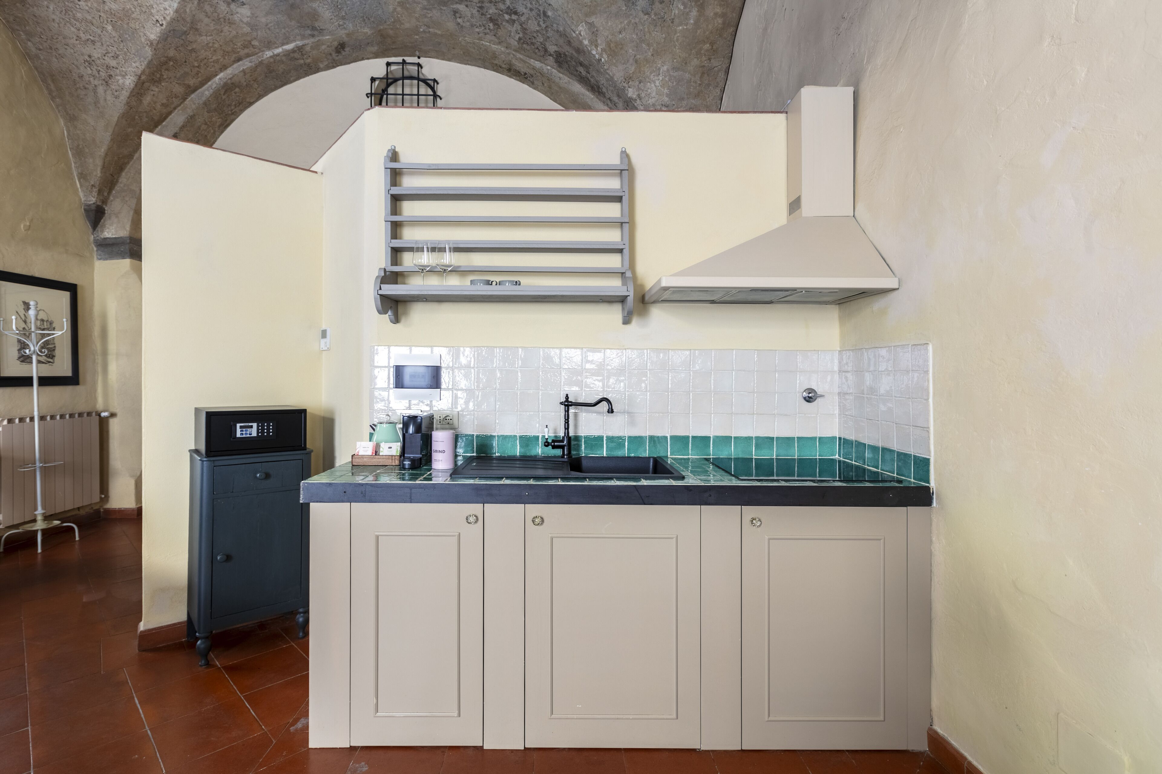 A kitchen with a built-in sink, a coffee machine, and a small cabinet.
