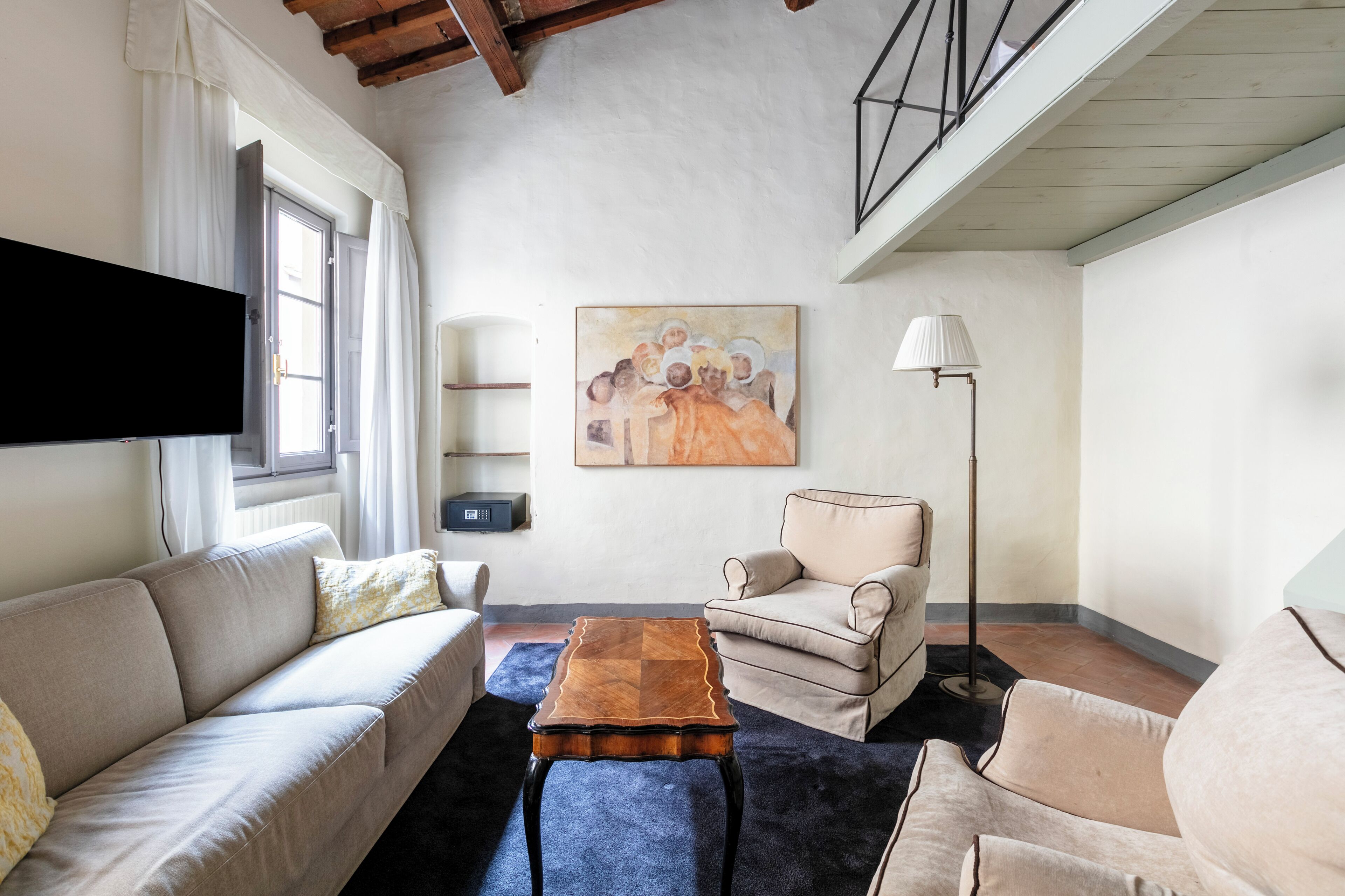 A living room with a sofa, armchair, coffee table, and artwork on the wall.