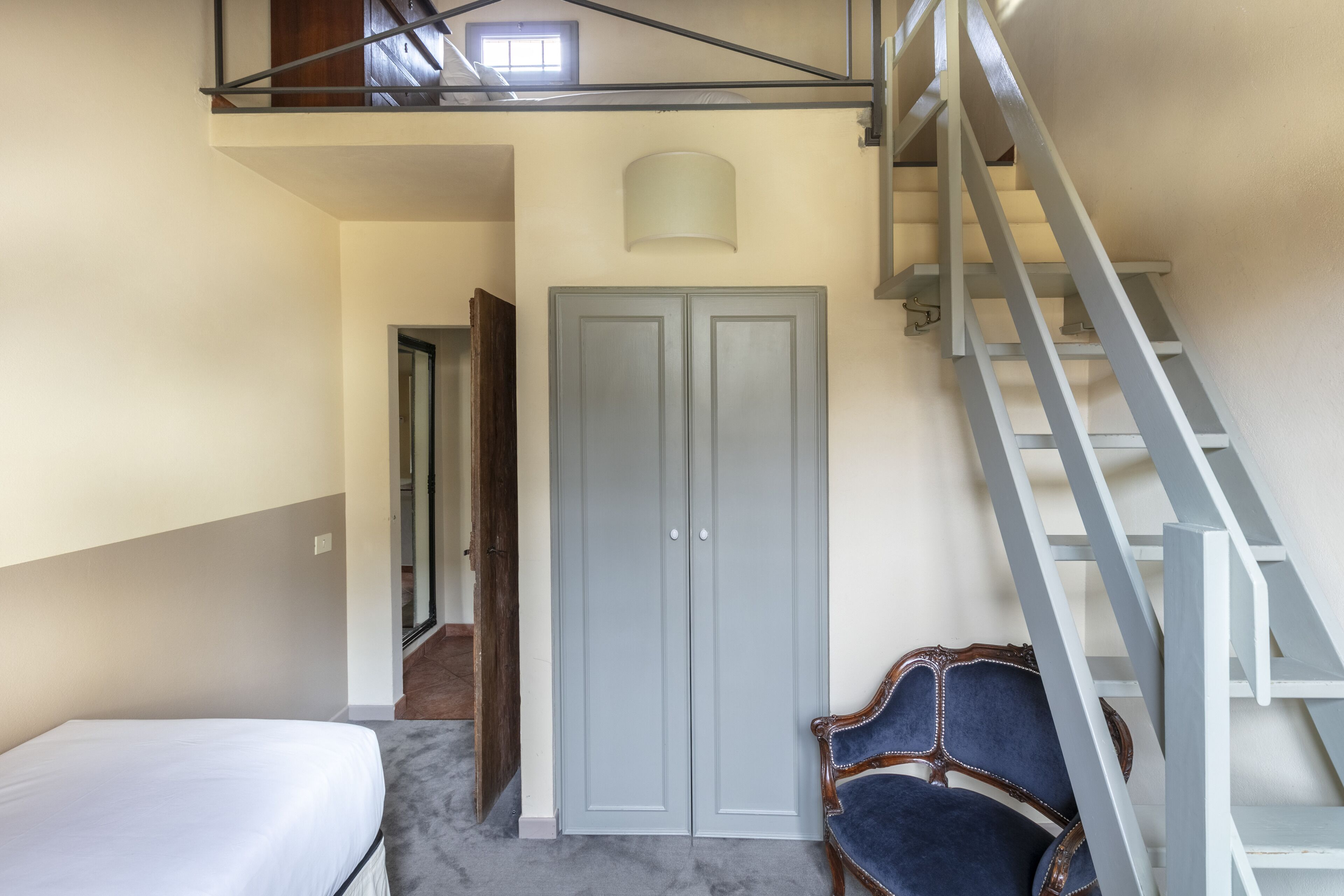 A room with a bed, a wardrobe, and a staircase.