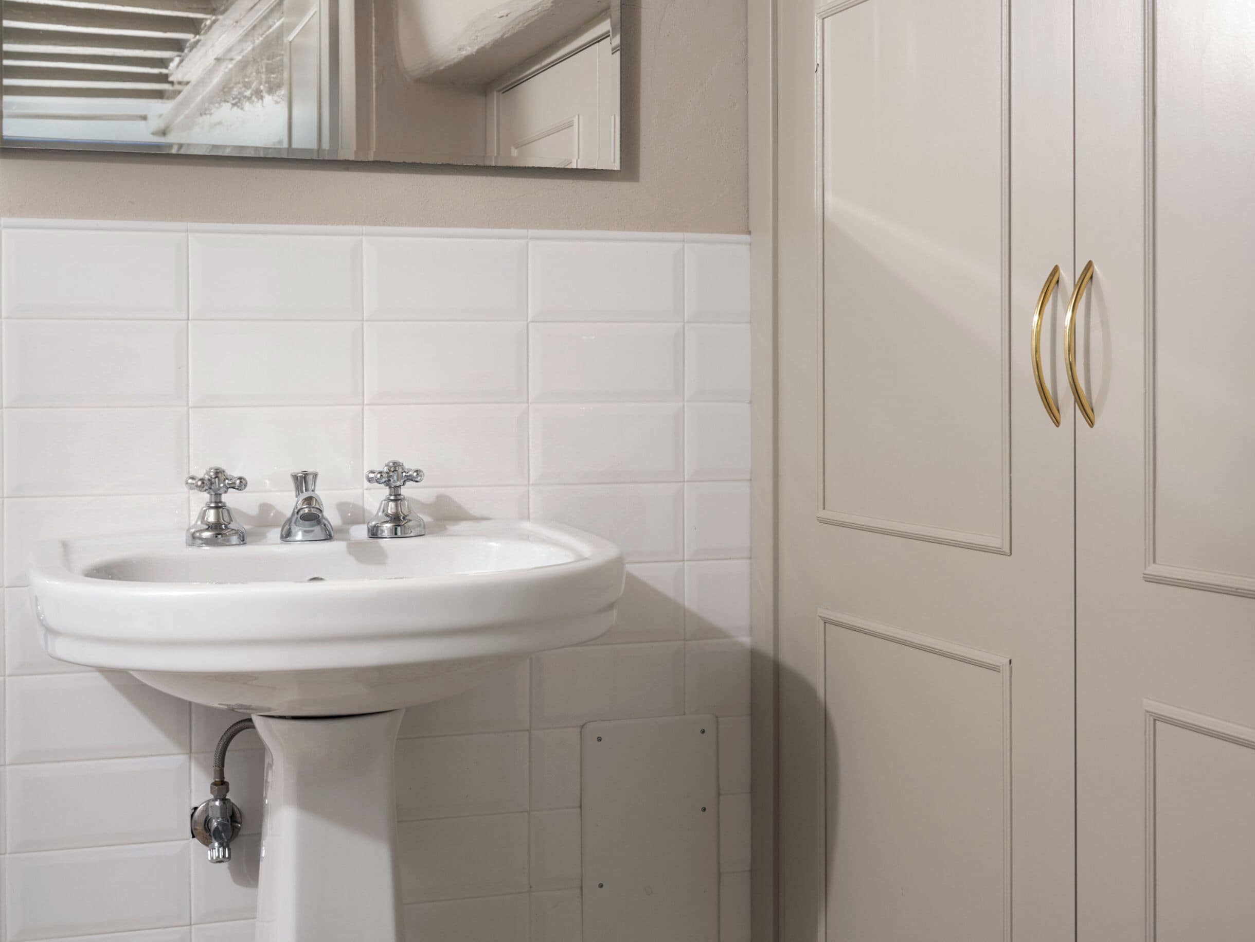 Un baño con un lavabo blanco, tres grifos y un espejo encima.