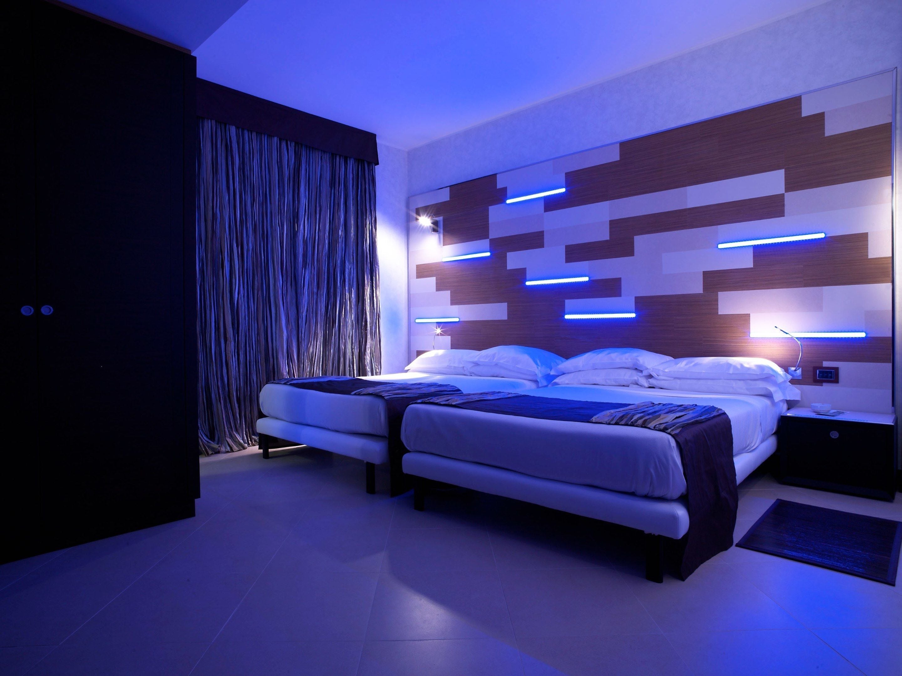 A modern bedroom with a double bed, a nightstand, and a wall-mounted light fixture.