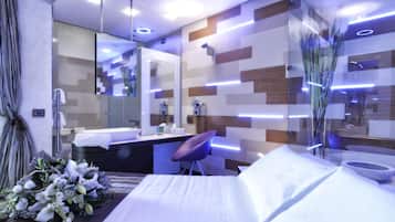 A modern hotel room with a large bed, a vanity with a mirror, and a bathroom with a shower.